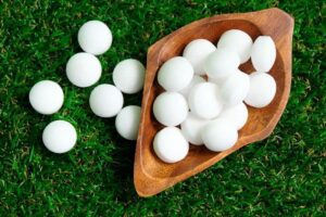 Wooden bowl of mothballs on grass