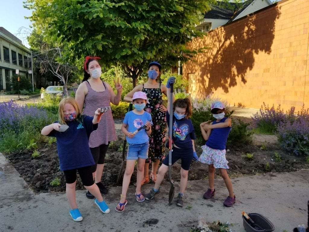 Six people hold gardening tools and embody the spirit of Planting Hope together