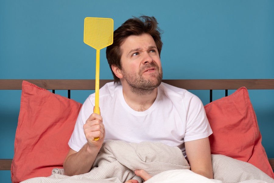 Young caucasian man holding a fly swatter wanting to kill annoying mosquito Pest Control