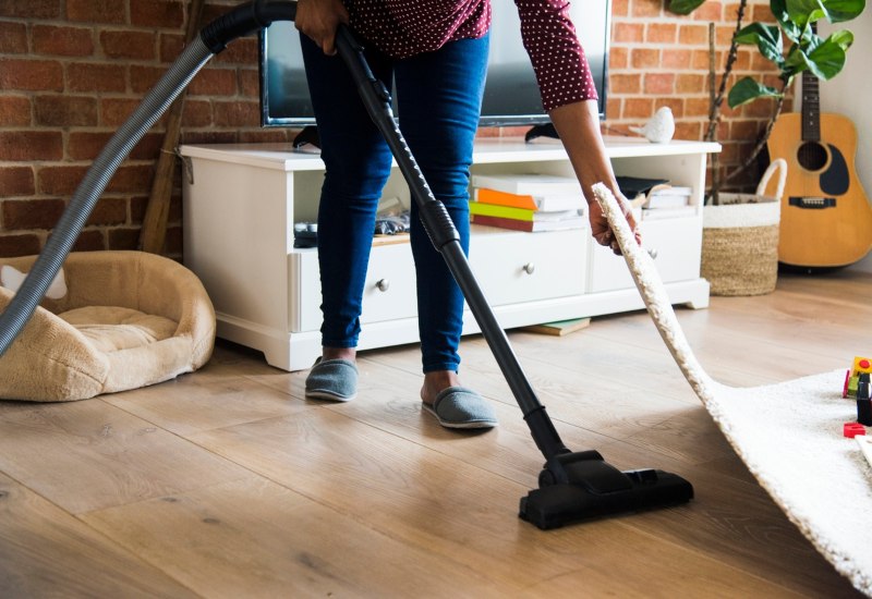 A woman vacuuming a room in a pest-free house in Chicago, keeping her space clean and tidy.