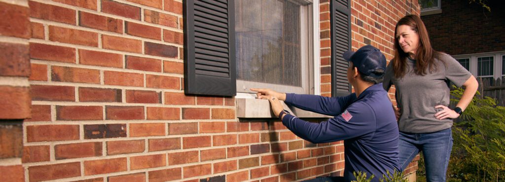 rose pest solutions technician showing homeowner a tear in a window screen where potential mice could get in