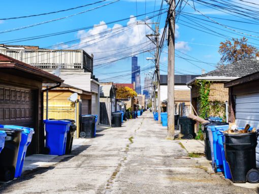 Chicago alley with trash bins, garages, and the city skyline in the background