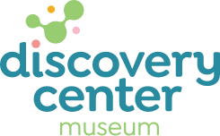 Discovery Center Museum logo with stylized green and orange molecular shapes above the words “discovery center” in blue and “museum” in light green below.